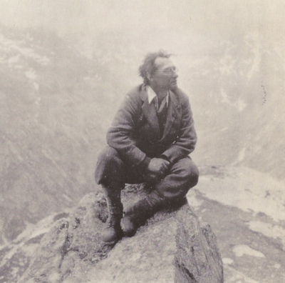 I.A. Richards seated on a rock in a mountainous landscape.